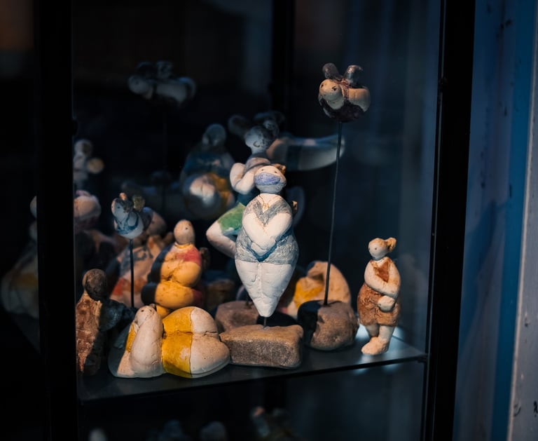 Diverse Gipsengel auf Steinsockeln in einer Glasvitrine