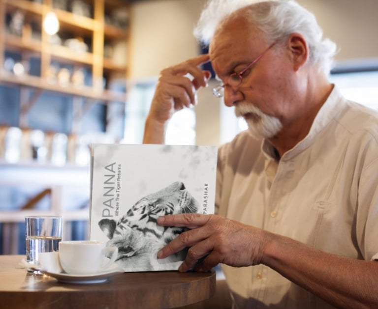 a man sitting at a table with a book and a cup of coffee