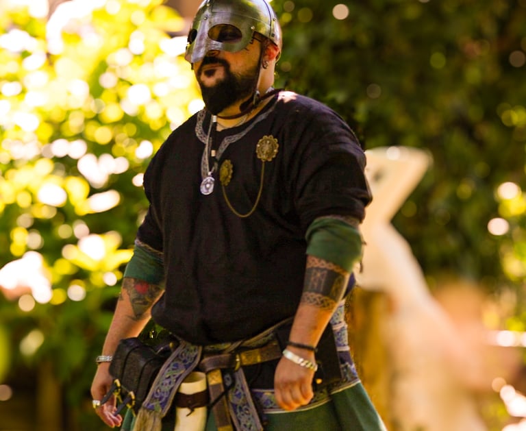 Hombre en ceremonia de boda medieval con chaleco y espada ornamental en un entorno forestal