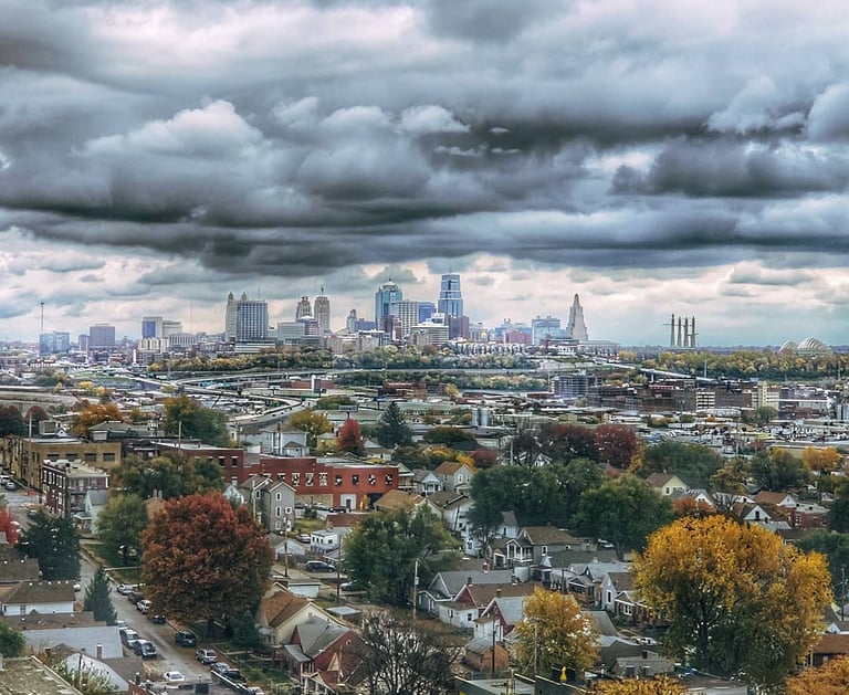 Downtown Kansas City, Missouri landscape photo taken during the fall with vibrant trees and deep, cloudy skies.