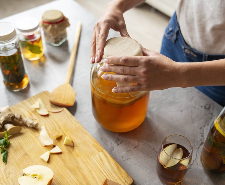 Una mujer prepara té de kombucha casero en un frasco de vidrio con un SCOBY.
