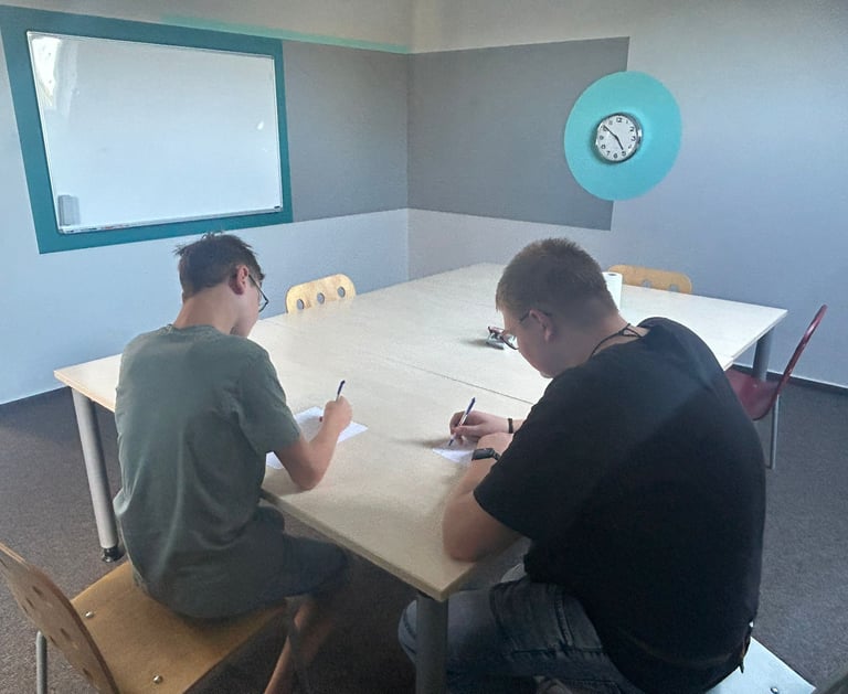 two men sitting at a table with papers and pens