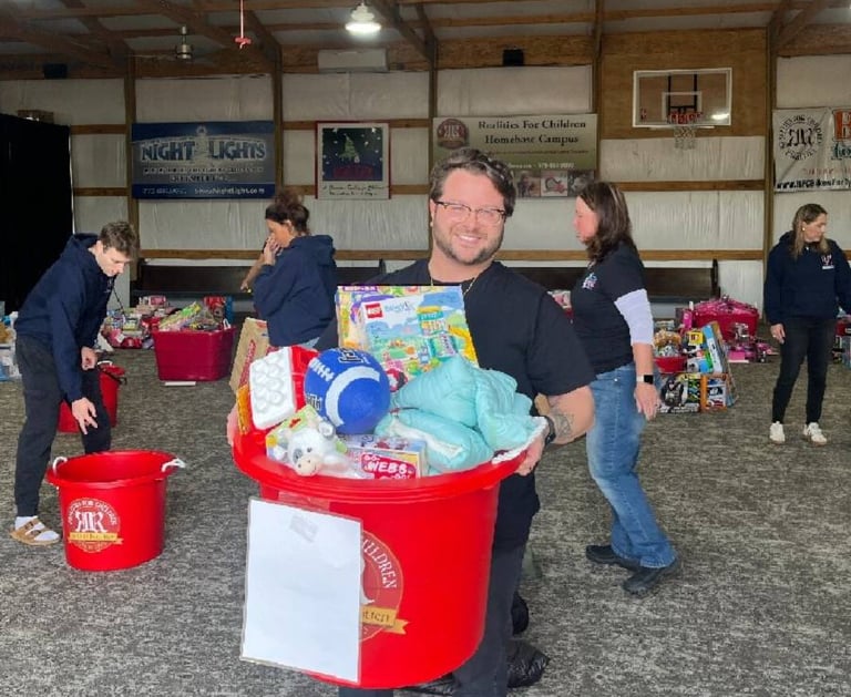 Team member from Edge Optics holding a large bin full of donated toys