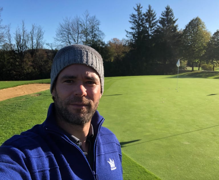 a man in a blue jacket and a hat on a golf course