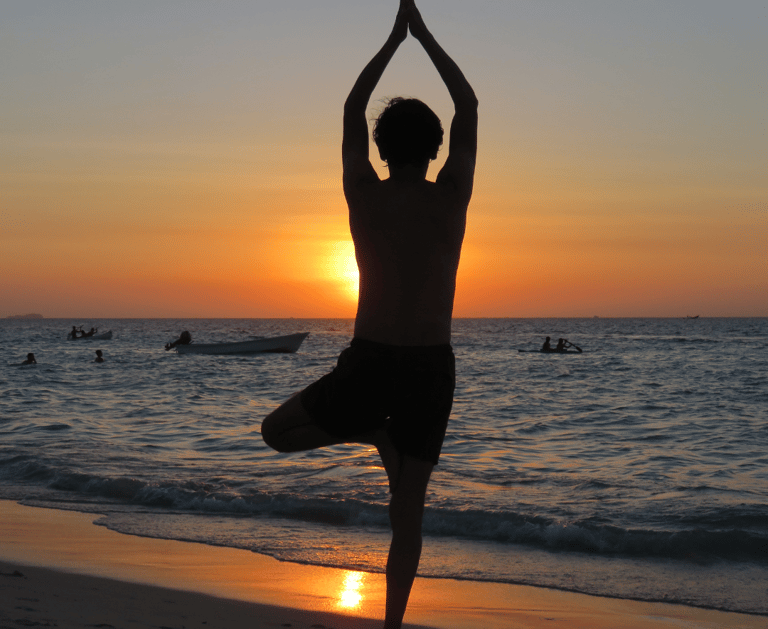 a man standing on a beach with a sunset in the background