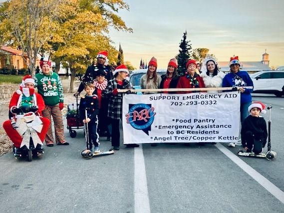 Group of Emergency Aid of Boulder City volunteers dressed for BC Christmas parade with banner