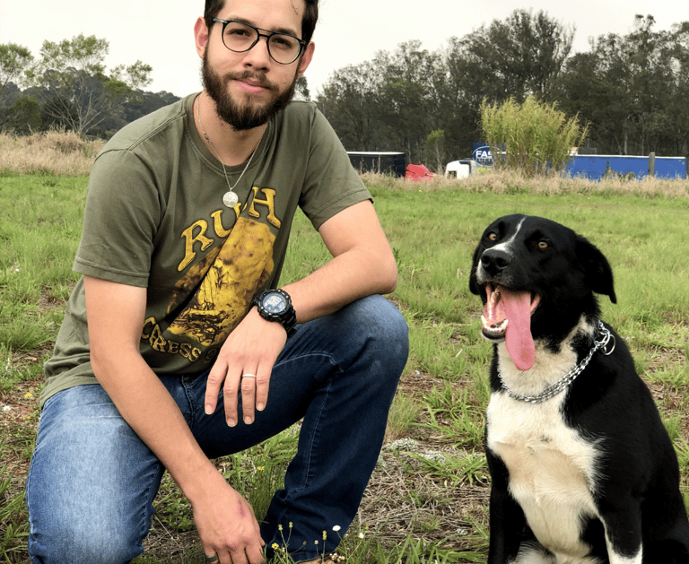 o adestrador alvaro israel agachado de lado de um cão tranquilo