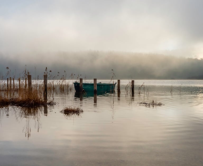 a boat on a lake with foggy sky