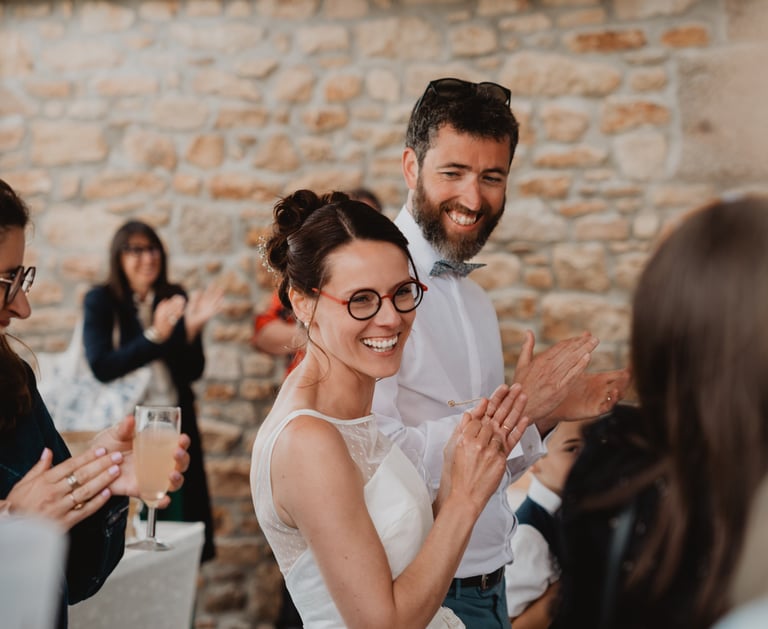 deux mariés heureux et souriant entourés de leurs invités