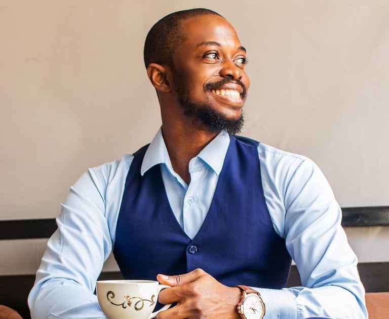 a man wearing a blue semi-formal attire holding a cup of tea