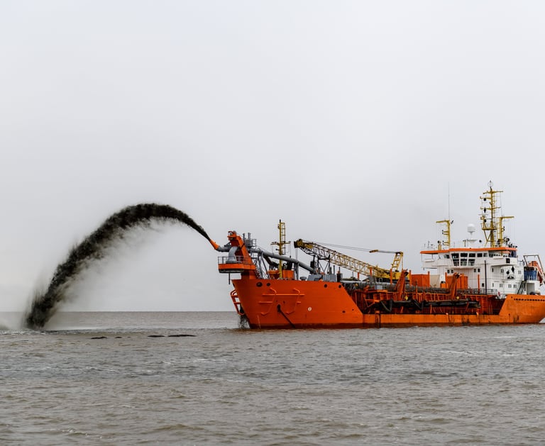 a boat with a large amount of dredging material coming out of the water