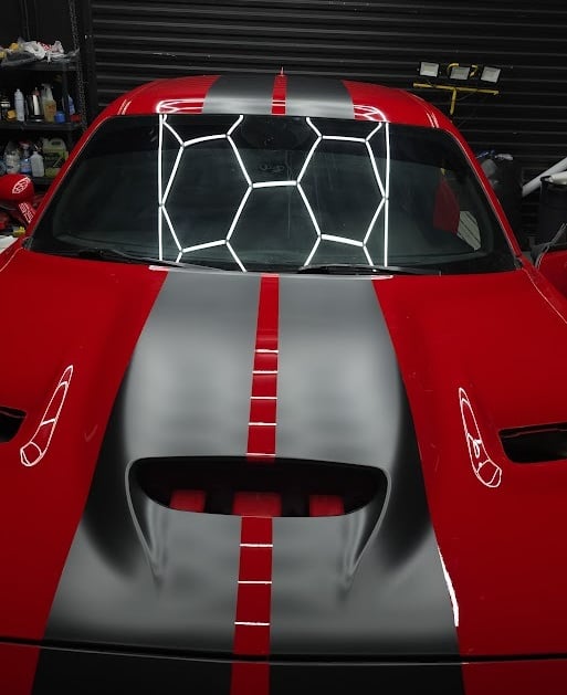 Red Dodge Challenger with silver racing stripes and honeycomb vinyl accents