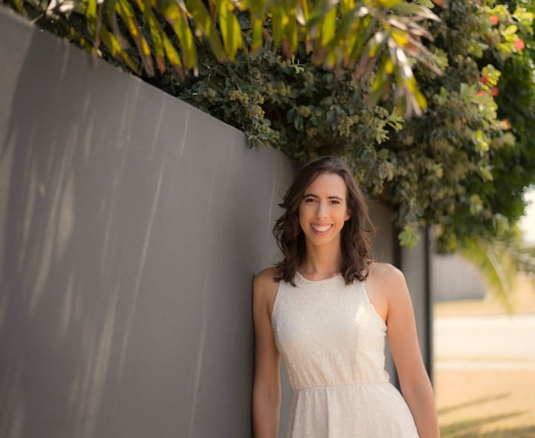 a woman in a white dress standing next to a wall