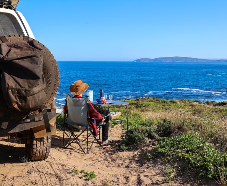 Toeristen genieten van hun kamping plekje aan het water met een 4WD
