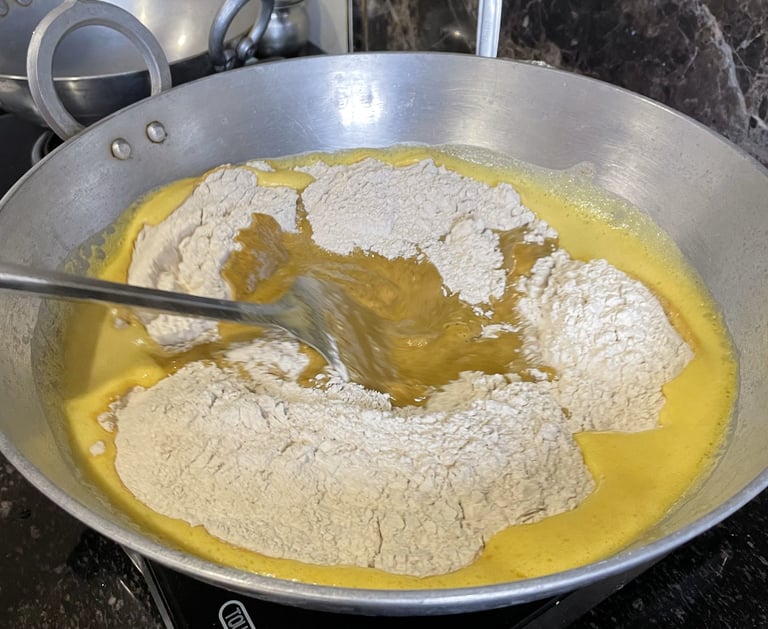 Chickpea flour being added to ghee and whole wheat flour
