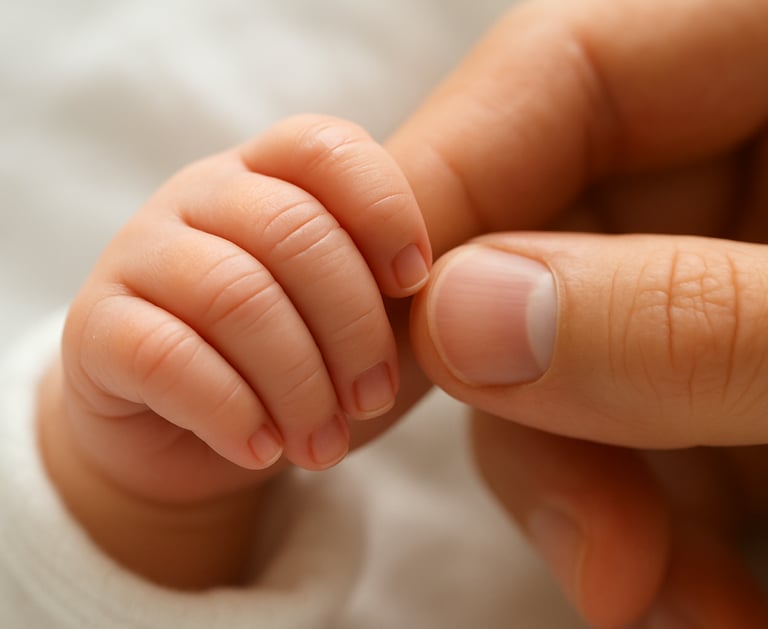 a newborn baby's hand wrapped around the mother's finger