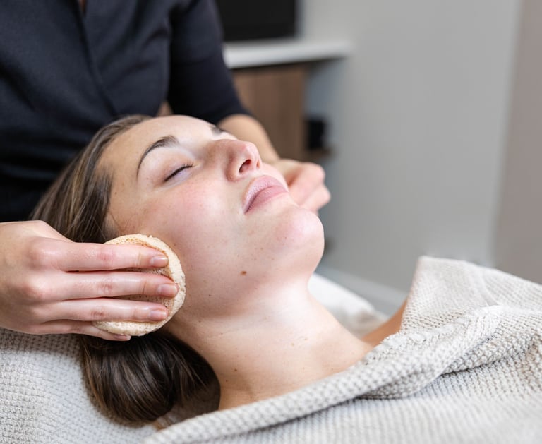 a woman getting a facial mask with a sponge at a salon