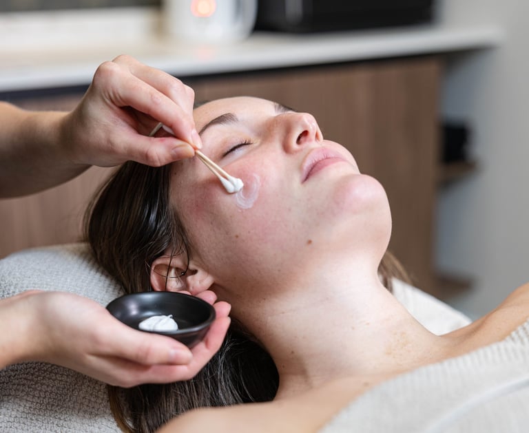 a woman getting her face covered in a mask at a salon