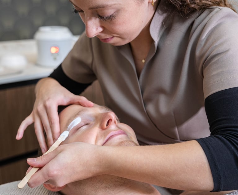 a man getting his eyebrows waxed at a salon