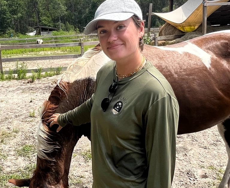 Sierra Sawtelle in a hat and a hat standing next to a horse