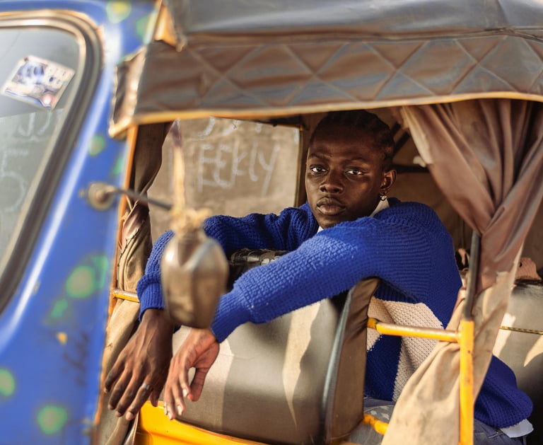 a man in a blue sweater sitting in a tuk tuk