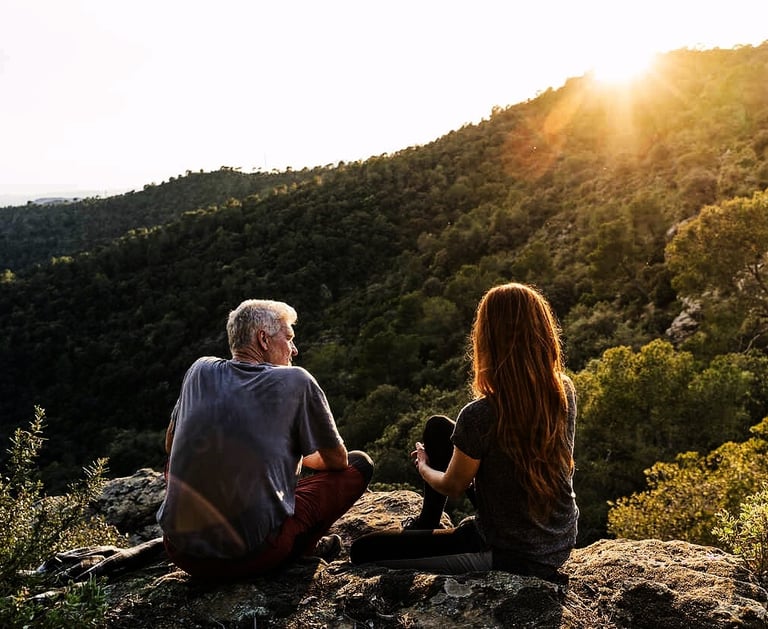 a man and woman sitting on a rock
