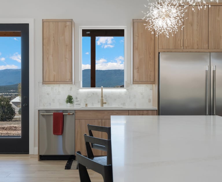 Modern kitchen featuring wood cabinets, stainless steel appliances, and a marble backsplash with mountain views.