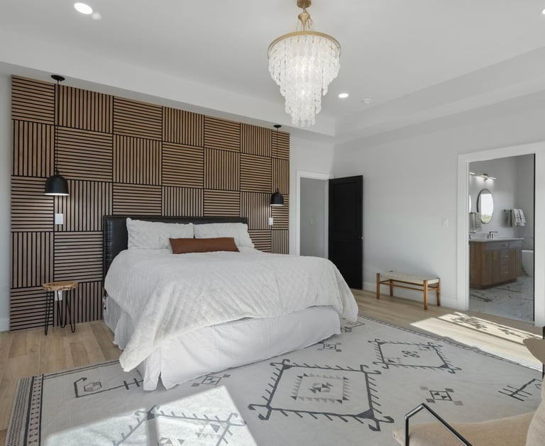 Modern bedroom featuring a wood slat accent wall, white bedding, and a luxury crystal chandelier.