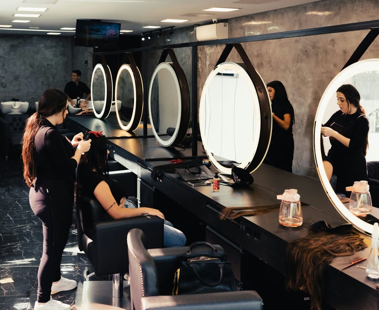 Estilistas profesionales trabajando en estaciones modernas de salón con espejos