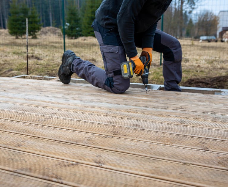 handyman drilling and building an outdoor wooden deck at an Auckland property