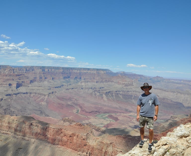 a man standing on a cliff overlooking a vast view of the grand canyon