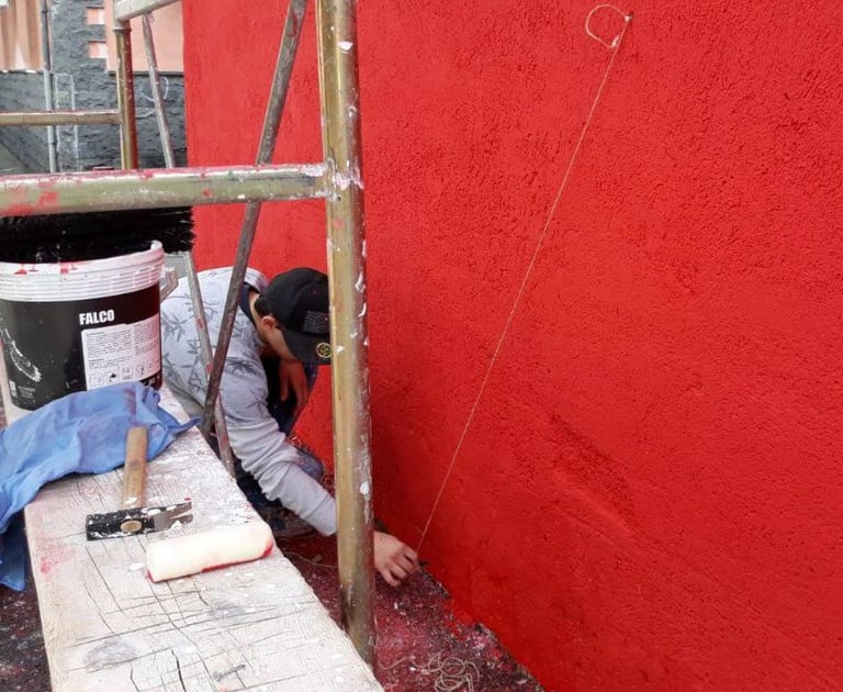 Poliops preparing the red base of a large urban mural, first stage of the exterior painting.