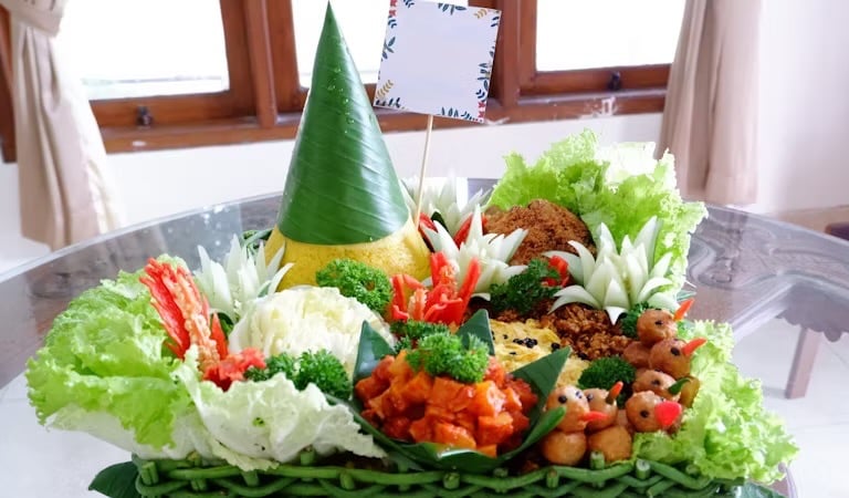 immagine di un piatto colmo di verdure e frutta con un cappello verde e giallo 