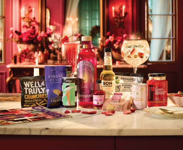 foto di tanti prodotti da mangiare disposti su un tavolo con petali di rosa e sfondo rosa elegante