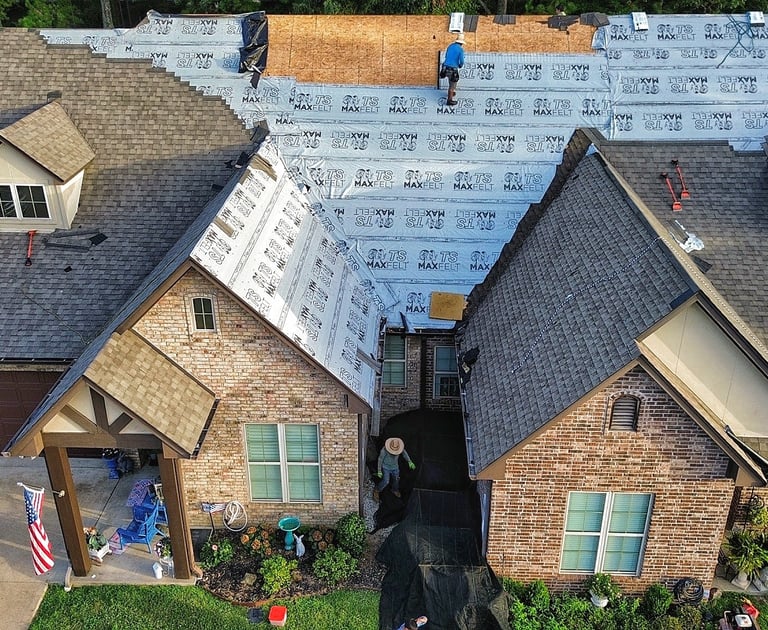 Roofing crew lays synthetic underlayment on roof replacement job for condominiums in Tyler, TX
