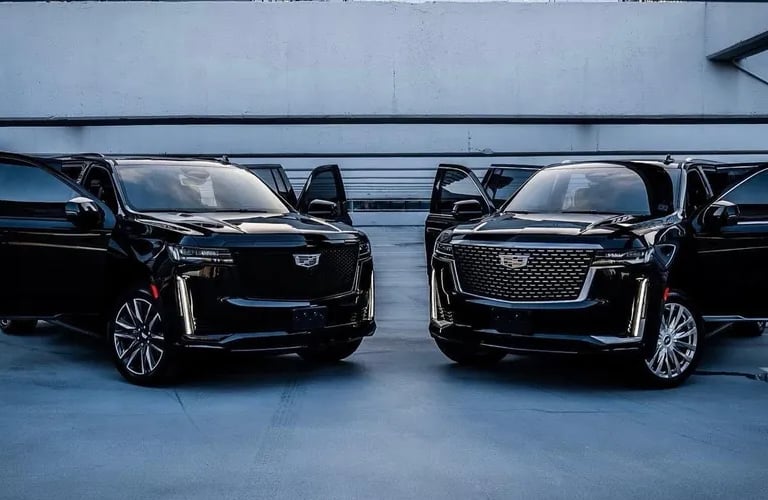 a black cadillac suv with a black car parked in a parking lot