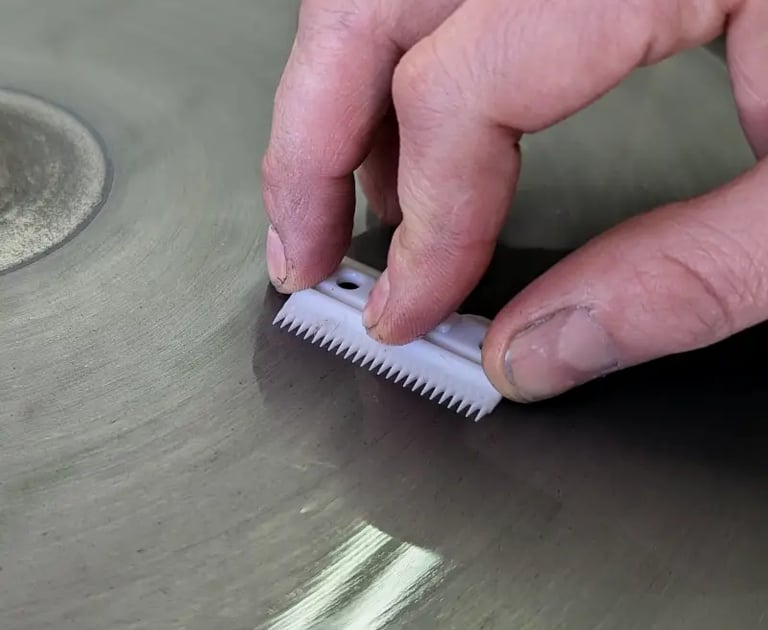 Clipper blade being hand-sharpened on diamond wheel