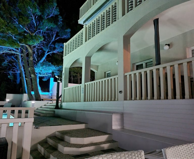 The photograph depicts the ground level of the house and a part of the yard with ambient light. 