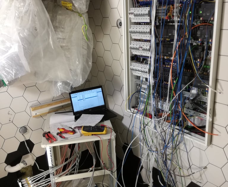 Electrician installing smart home automation wiring and circuit breakers in a wall-mounted panel.