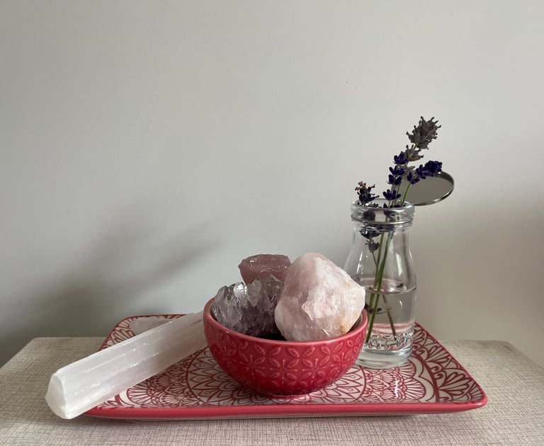 A bowl of crystals and a vase of flowers on a tray