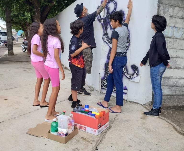 Jovem aplicando stencil – Estudante pratica a aplicação de stencil em uma parede da escola.