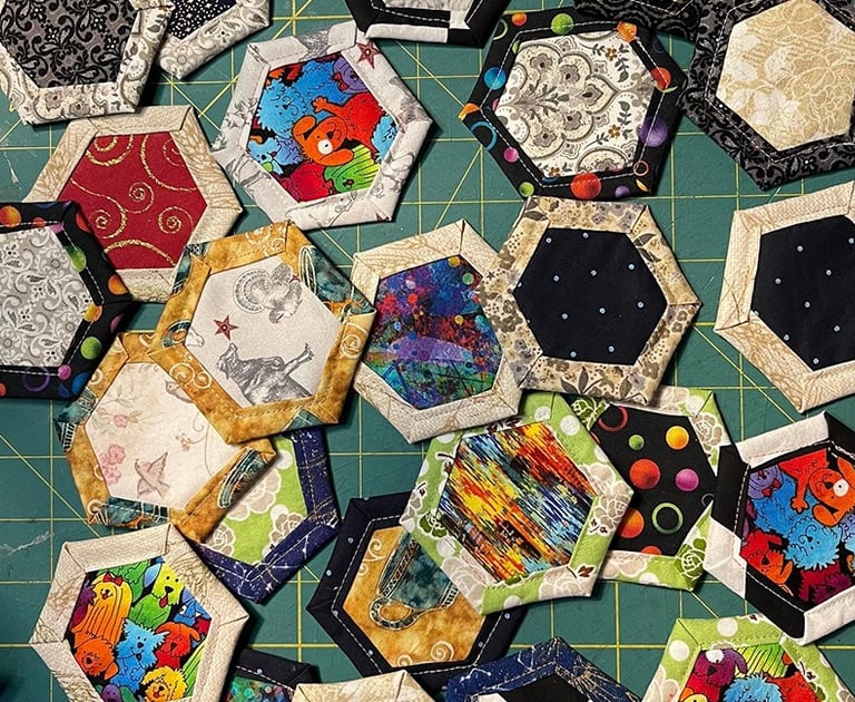 a bunch of quilted fabric hexagons on a cutting board