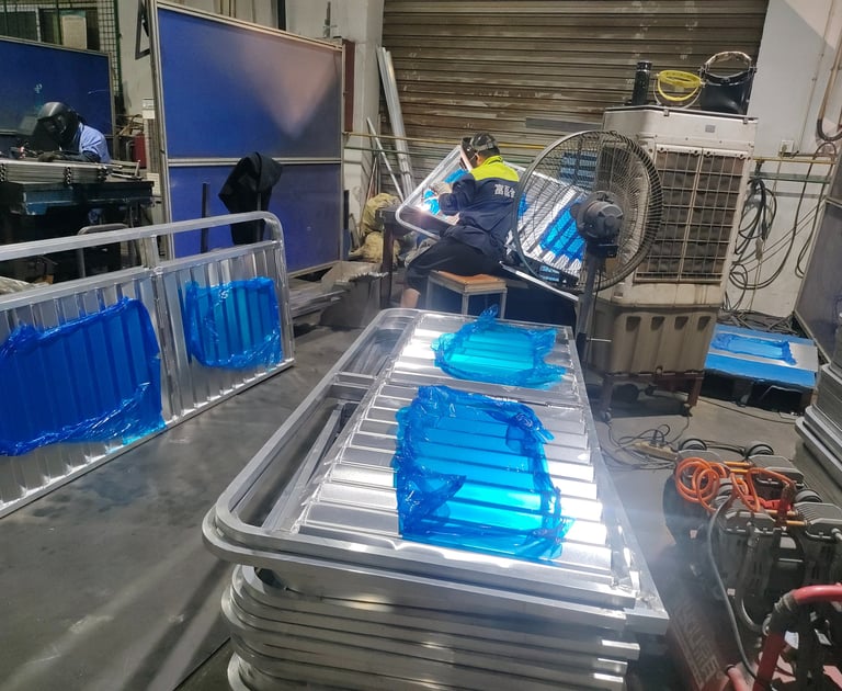 Professional welders fabricating aluminum frames in an industrial metal manufacturing workshop.