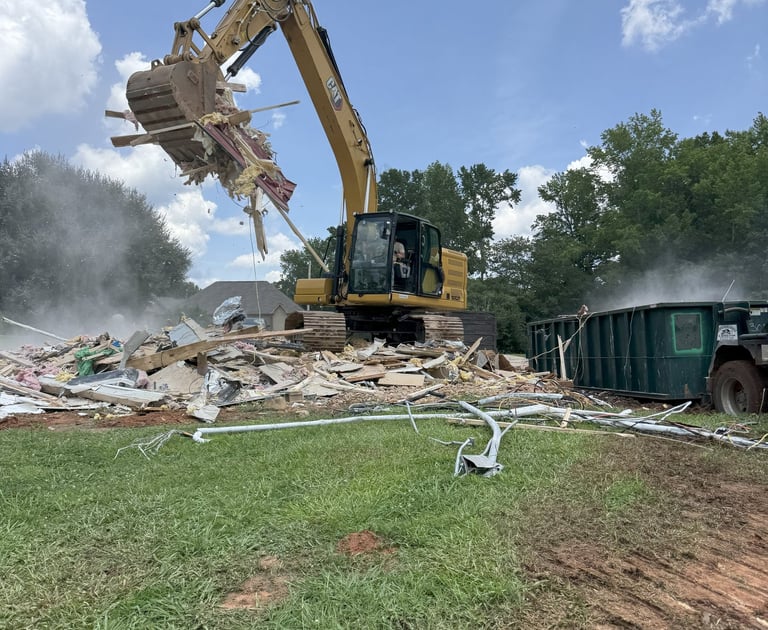 Excavator loading demolition debris in dumpster