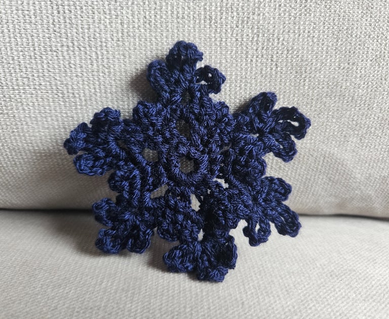 dark blue crochet snowflake on a light grey background