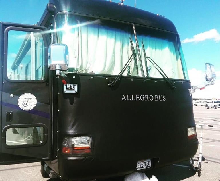 Front view of a black Tiffin Allegro Bus luxury motorhome with a protective leather bra cover.