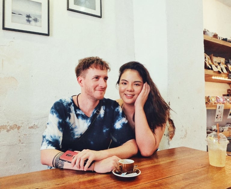 A happy young couple sitting together at a wooden table in a cozy cafe enjoying coffee.