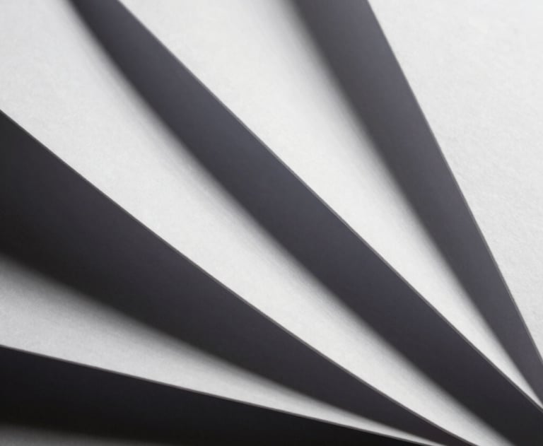 Abstract photography of white paper folds creating sharp geometric lines and deep shadows. Minimalist art style.