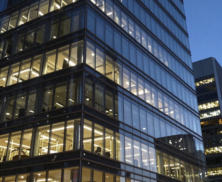 A professional photograph of a modern glass office building at night with lights reflecting on its sleek surface. North American / Global Financial Market.