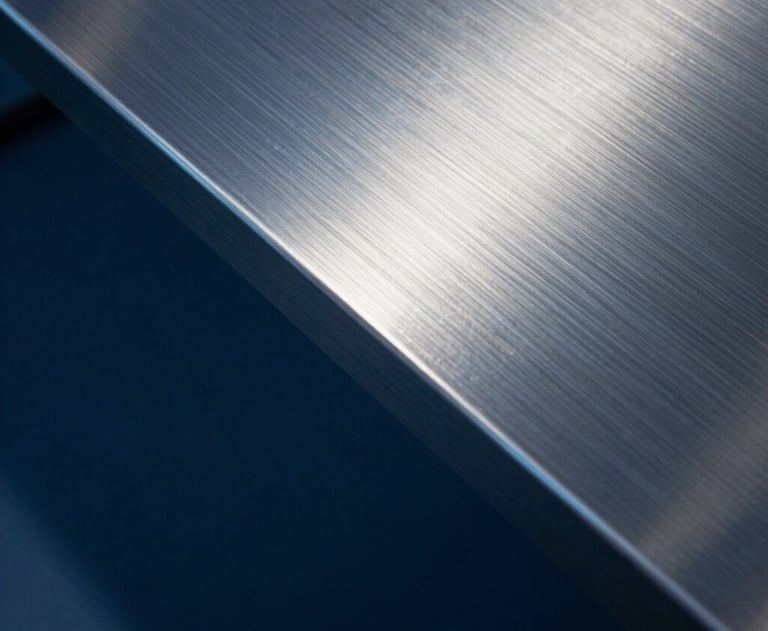 Abstract photography of light hitting a metal surface, creating reflections in navy blue and steel blue. Symbolic of precision, engineering, and modern efficiency.
